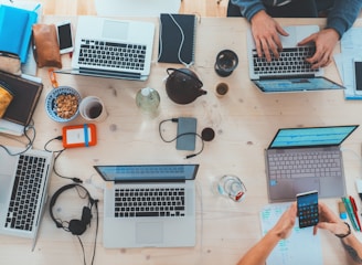 people sitting down near table with assorted laptop computers